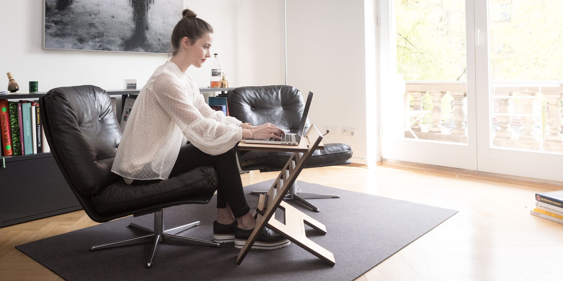 A person working comfortably on a laptop raised to eye level on a Palo stand